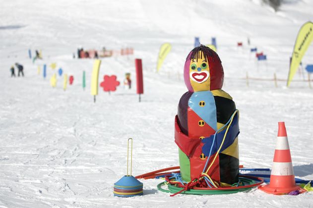 Verschneiter Übungshang mit bunten Slalomstangen und Figuren.