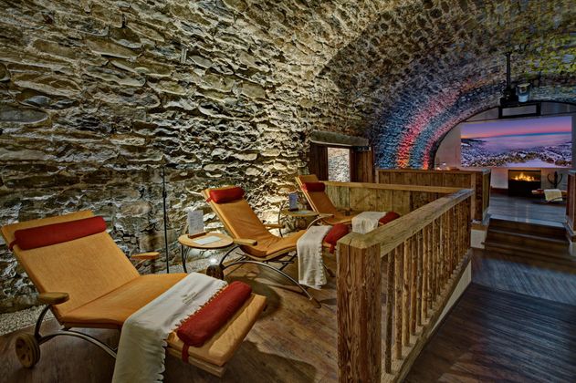 Ein stilvoller Wellnessbereich mit gemütlichen Liegen und einer natürlichen Steinwand. Die sanfte Beleuchtung schafft eine entspannte Atmosphäre.