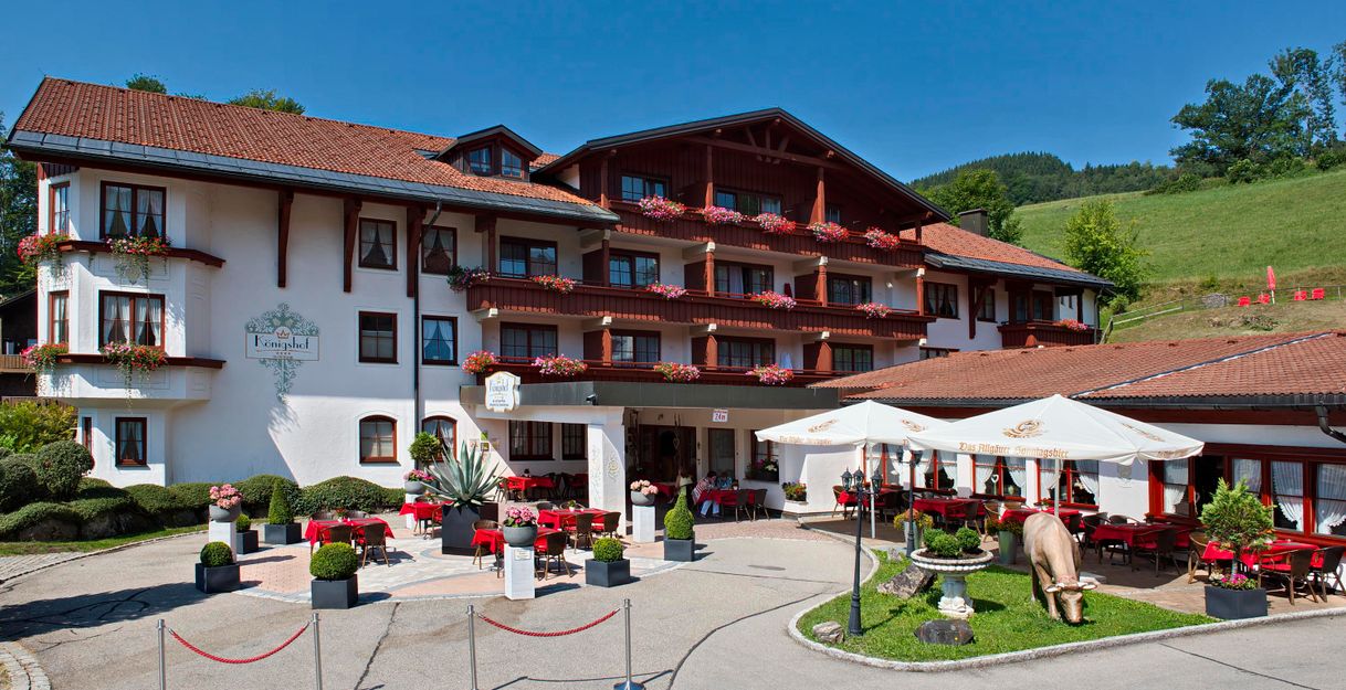 Ein charmantes Hotel mit traditioneller Architektur und schönen Balkonen. Der Außenbereich lädt mit Tischen und Sonnenschirmen zum Entspannen ein.