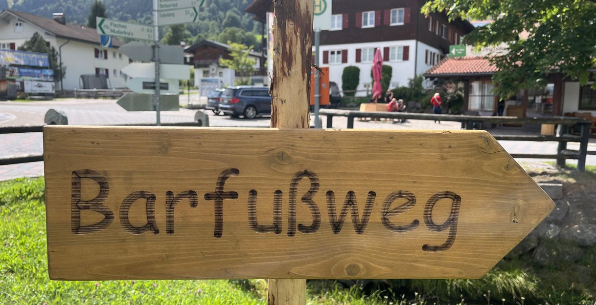 Ein hölzernes Wegweiserschild mit der Aufschrift "Barfußweg"