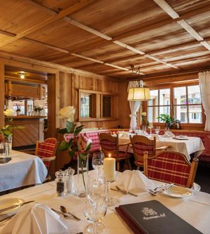 Ein gemütliches Restaurant mit Holzwänden und eleganten Tischdekorationen. Die Tische sind für Gäste vorbereitet und es gibt eine einladende Atmosphäre.