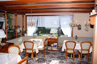 Ein gemütliches Restaurant mit Holzdekor und eleganten Tischen. Große Fenster lassen viel Licht herein und bieten einen Blick ins Freie.