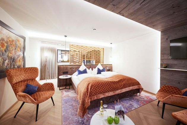 Ein modernes Hotelzimmer mit einem Doppelbett und stilvollen Möbeln. Die warmen Farben und die angenehme Beleuchtung schaffen eine gemütliche Atmosphäre.