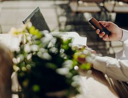 Mann sitzt draußen an einem Laptop und Arbeitet