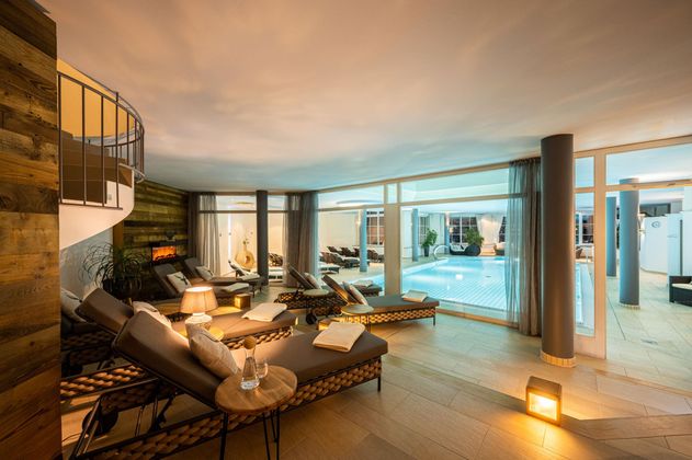 Ein eleganter Wellnessbereich mit Liegen und einem Innenpool. Die sanfte Beleuchtung schafft eine entspannende Atmosphäre.