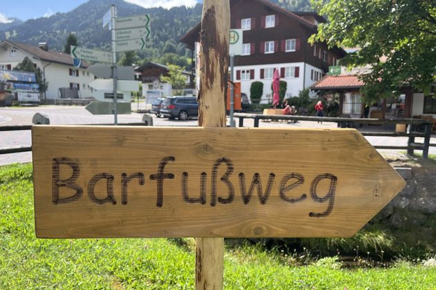 Ein hölzernes Wegweiserschild mit der Aufschrift "Barfußweg"