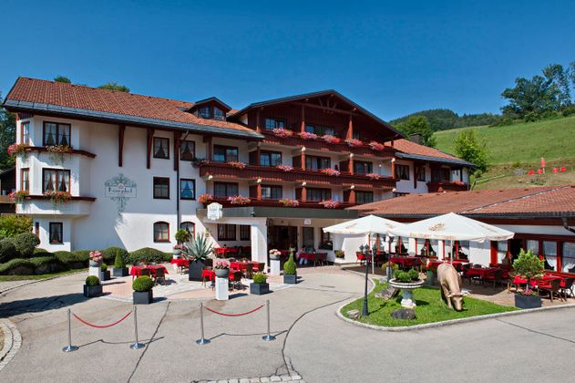 Ein charmantes Hotel mit traditioneller Architektur und schönen Balkonen. Der Außenbereich lädt mit Tischen und Sonnenschirmen zum Entspannen ein.