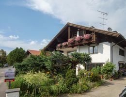 A charming house with a beautiful garden and blooming plants. The sky is clear and it is a sunny day.