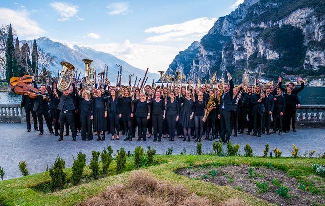 Im Bild ist die Stadtkapelle Memmingen zu sehen mit ihren Instrumenten in der Hand und dem Gebirge im Hintergrund