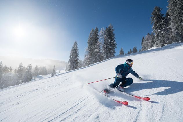 <p>Ein Skifahrer in blauem Anzug fährt eine steile Skipiste hinab.</p>