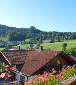Eine malerische Landschaft mit grünen Hügeln und traditionellen Häusern. Bunte Blumen blühen vor einem charmanten Gebäude.