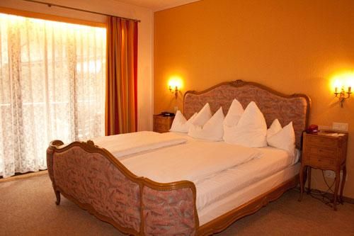 Ein gemütliches Schlafzimmer mit einem großen Bett und eleganten Kissen. Große Fenster lassen viel Tageslicht hereinfällen.