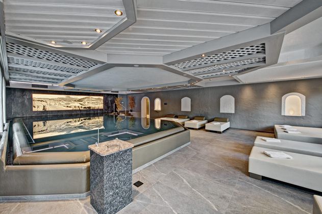 Ein eleganter Wellnessbereich mit einem großen Schwimmbad und modernen Liegen. Die Umgebung ist hell und einladend, ideal zur Entspannung.