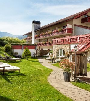 Ein einladender Außenbereich eines Hotels mit einer gepflegten Rasenfläche und Liegen. Im Hintergrund sind mehrere Stockwerke des Gebäudes mit Balkonen zu sehen.