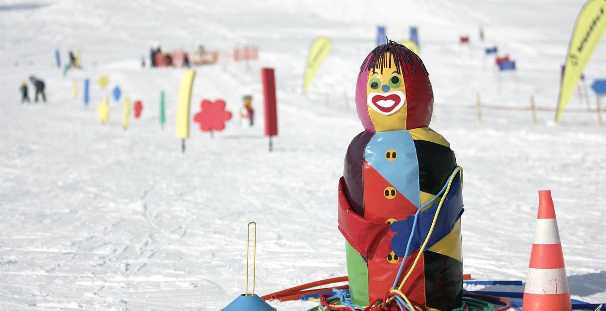 Verschneiter Übungshang mit bunten Slalomstangen und Figuren.