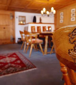 Ein gemütliches Restaurant mit rustikaler Holzdekor und einem schönen Teppich. Im Vordergrund ist ein kunstvoll geschnitzter Stuhl zu sehen.