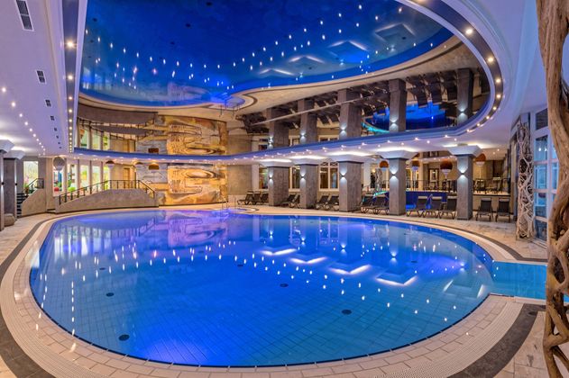 Ein eleganter Innenpool mit blauem Wasser und stimmungsvollem Licht. Die Umgebung ist modern gestaltet, mit gemütlichen Sitzecken und einer schönen dekoration.
