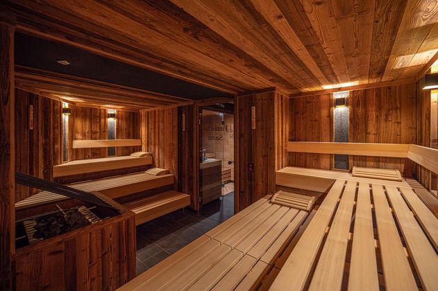 Eine stilvolle Sauna mit Holzverkleidung und bequemen Bänken. Sanftes Licht sorgt für eine entspannende Atmosphäre.