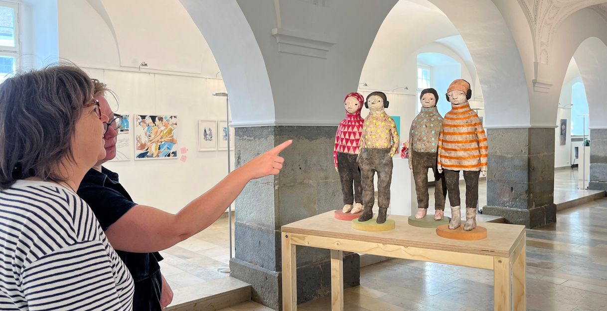 Personen berachten eine Skulptur im Rahmen einer Kunstausstellung