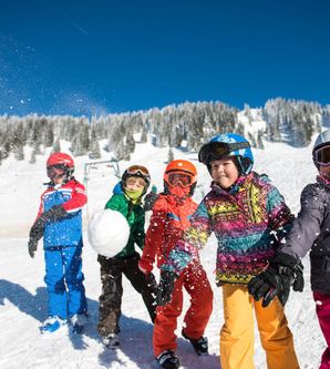 Fünf spielende Kinder im Schnee werfen Schneebälle.