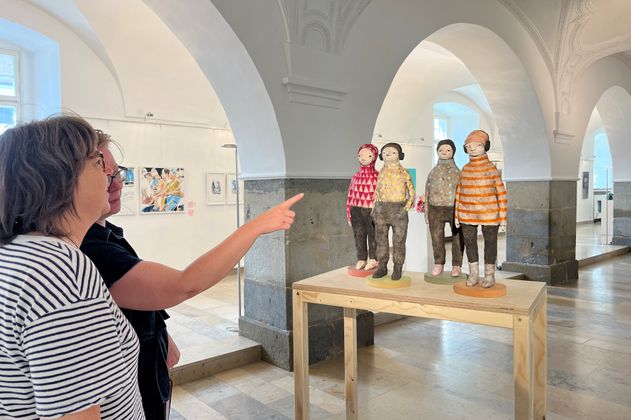 Personen berachten eine Skulptur im Rahmen einer Kunstausstellung