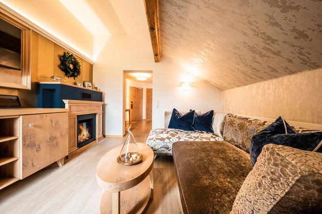 Ein gemütliches Wohnzimmer mit einer eleganten Couch und einem modernen Kamin. Die Wände sind hell und der Raum wirkt einladend und stilvoll.