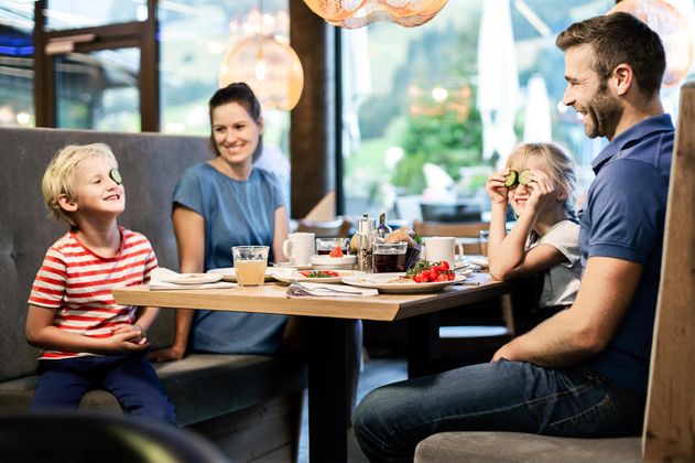 Eine Familie sitzt an einem Tisch in einem Restaurant und genießt das Frühstück. Die Stimmung ist fröhlich und entspannt.